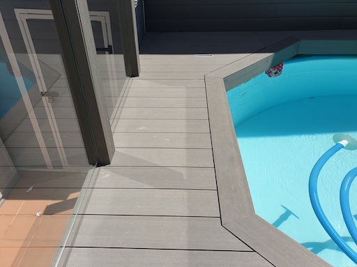 Colocación de tarima tecnologica de madera de ipe impermeable en una terraza con piscina y jardin