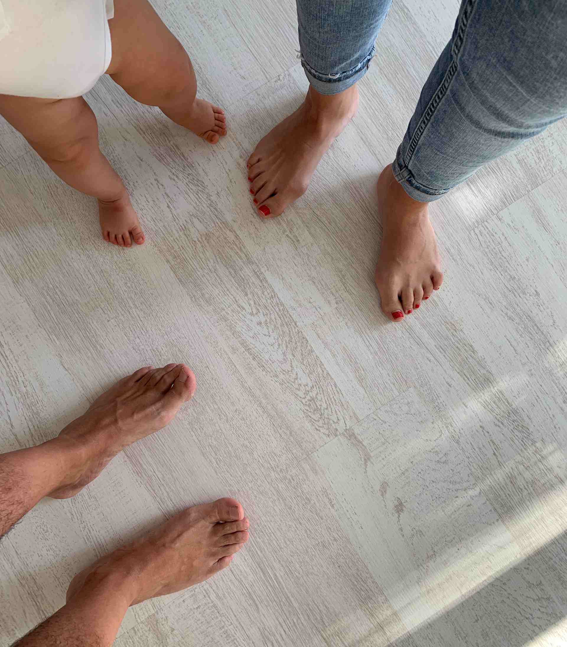 Familia pisando con los pies el parquet laminado quickstep roble irlandés de color blanco rústico