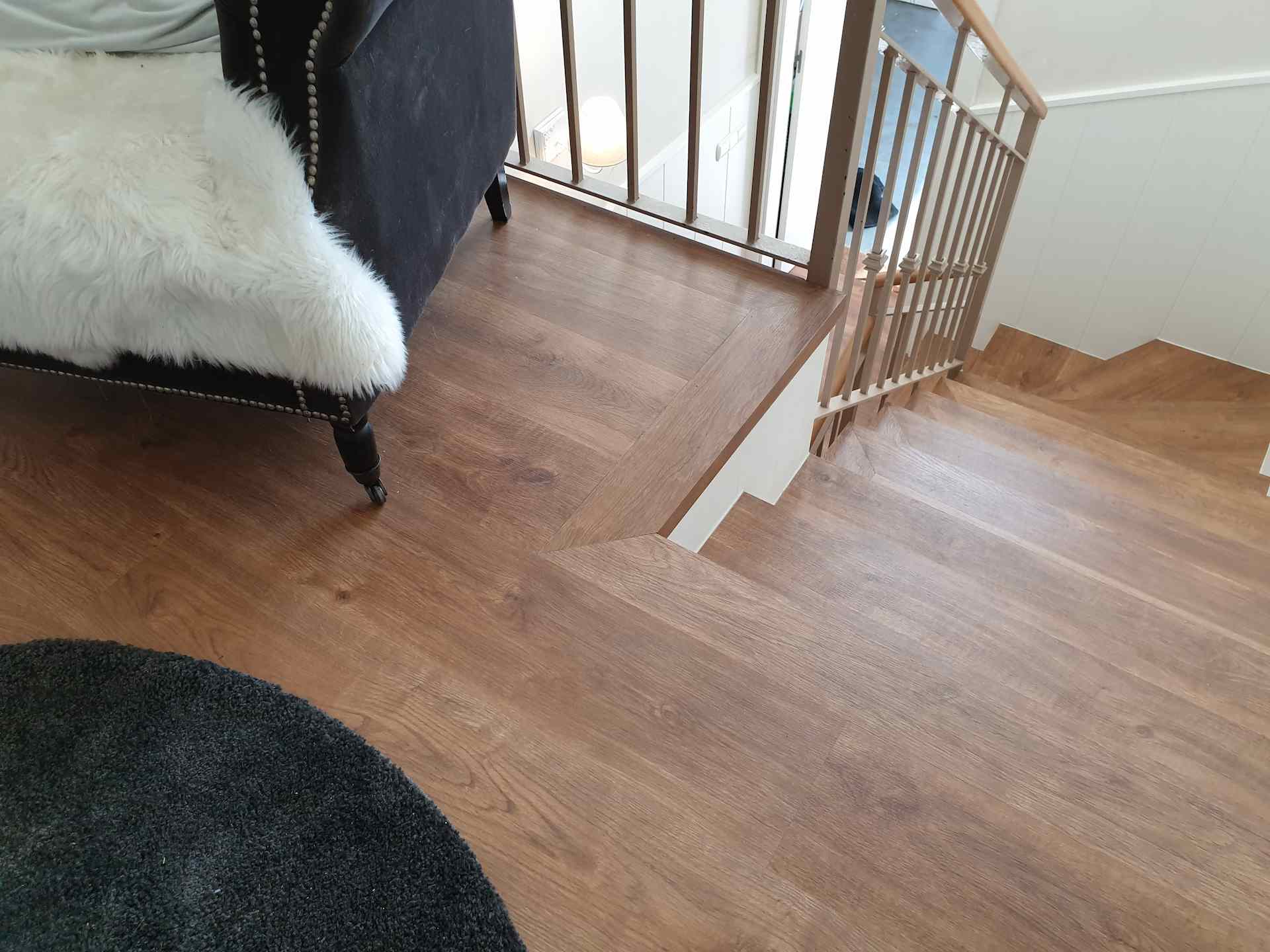 Colocación de parquet sintético de color marron oscuro con friso blanco en los dos pisos de una casa