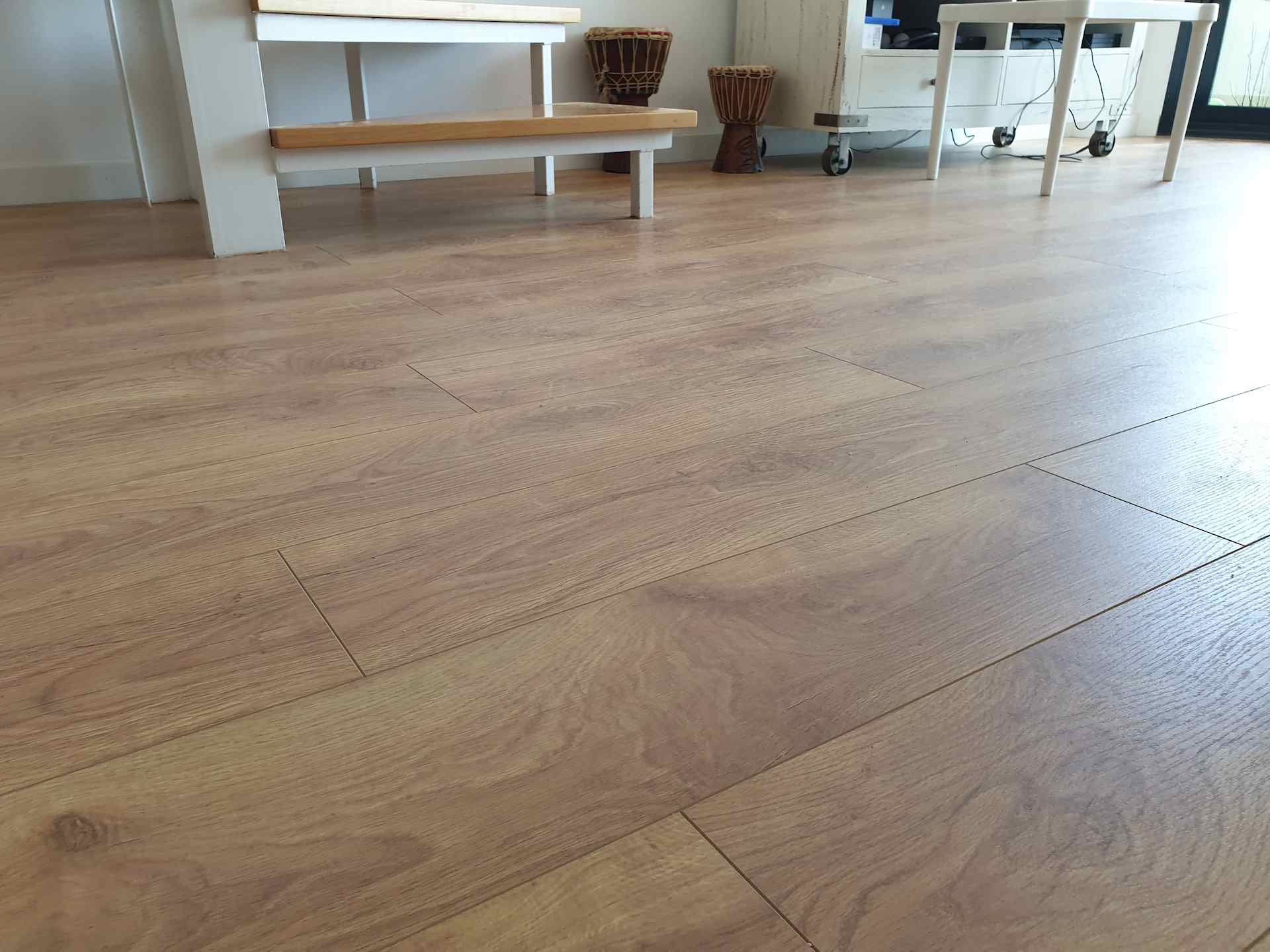 Montaje de tarima flotante marrón claro y de estilo nórdico en el comedor de un piso con escaleras