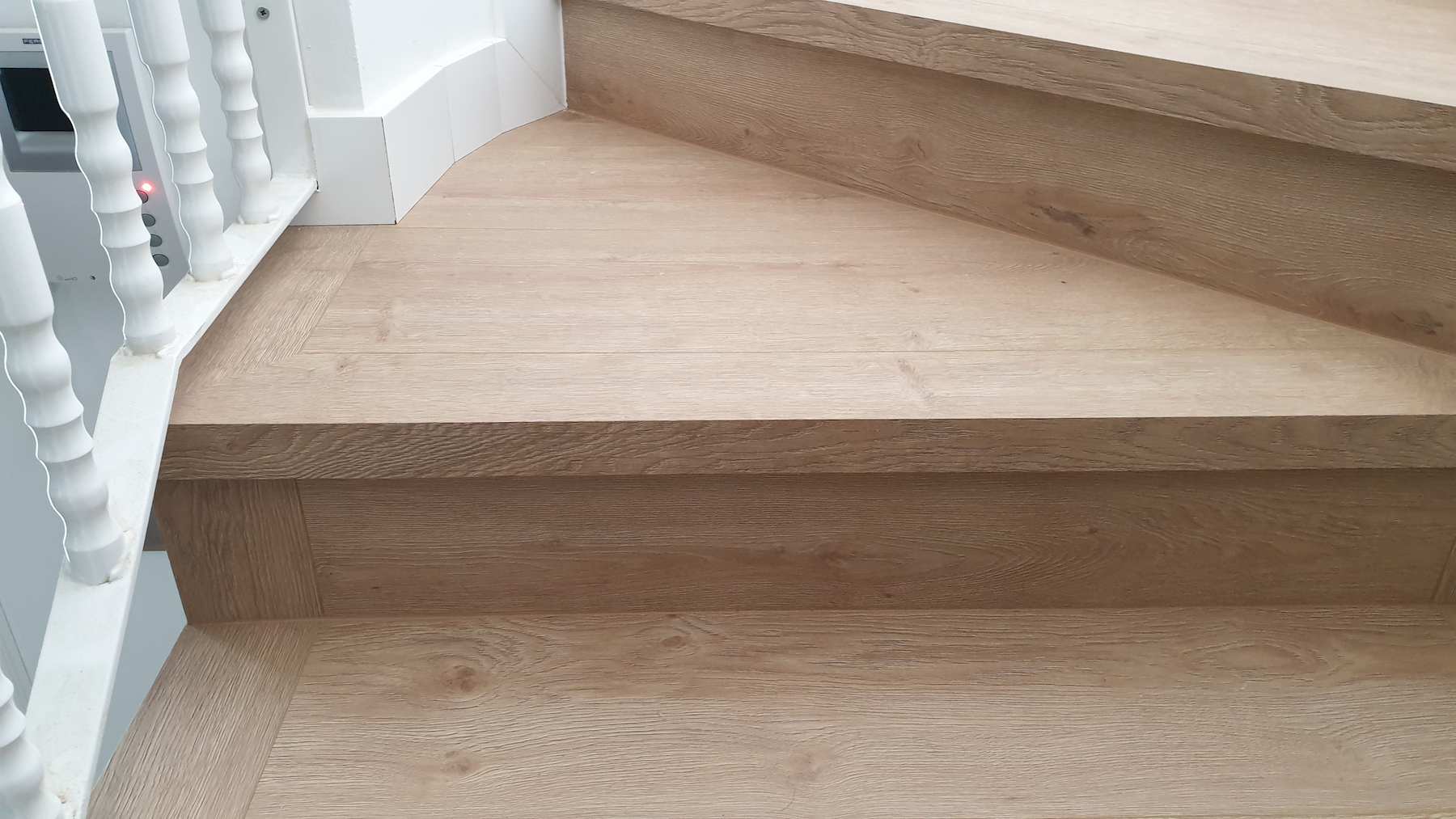 Parquet laminado multicapa sin bisel forrado en escaleras de caracol y con zócalo blanco