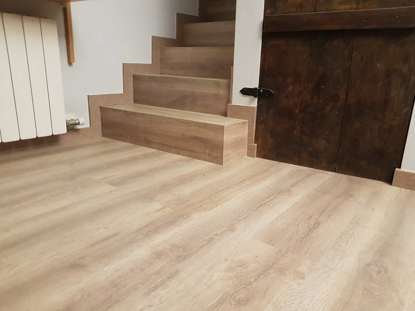 Instalación de madera flotante oscura en las escaleras de un recibidor con mamperlán machihembrado