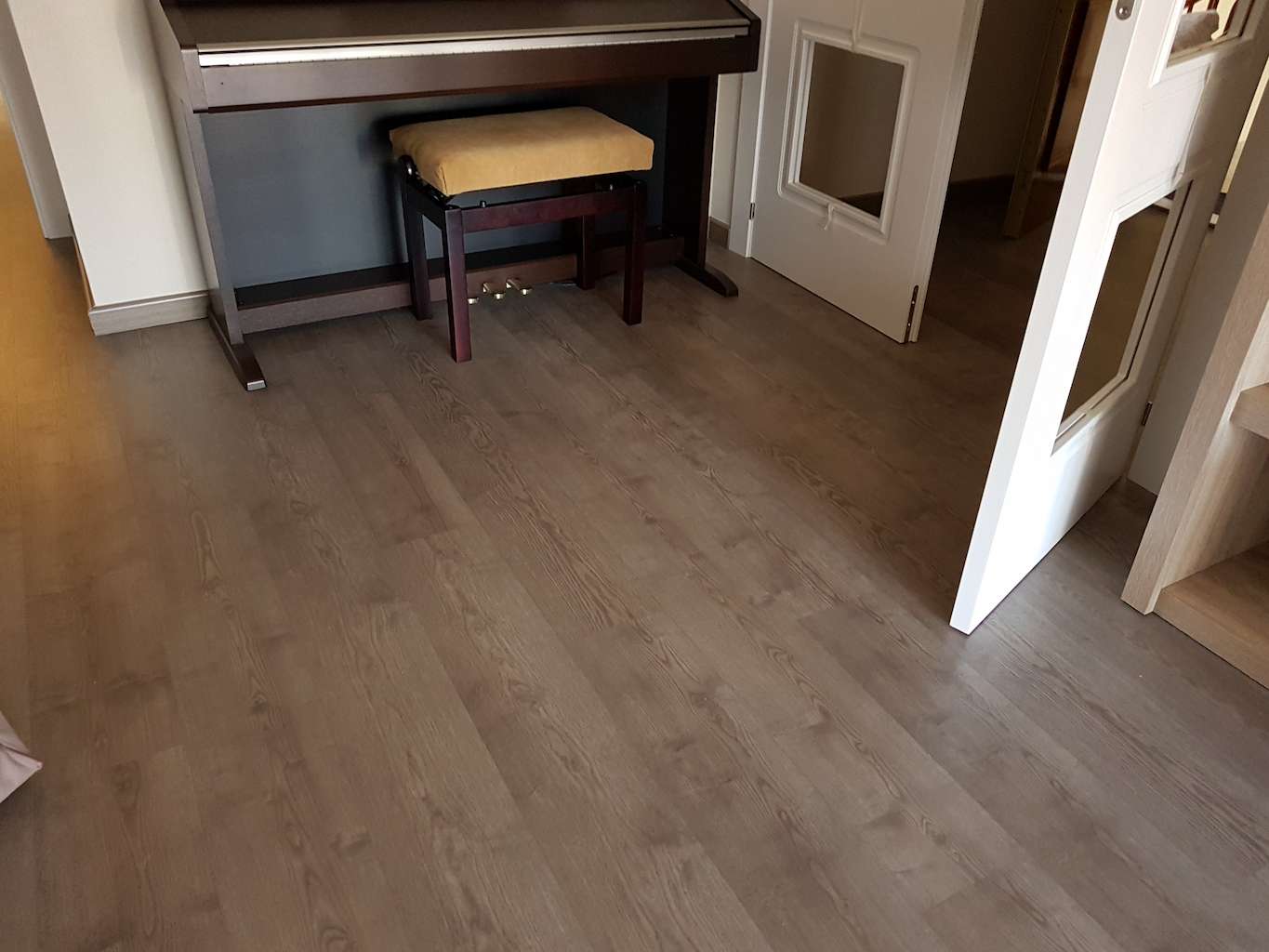 Montaje de tarima flotante AC4 de textura brillante en el interior de un salón con muebles