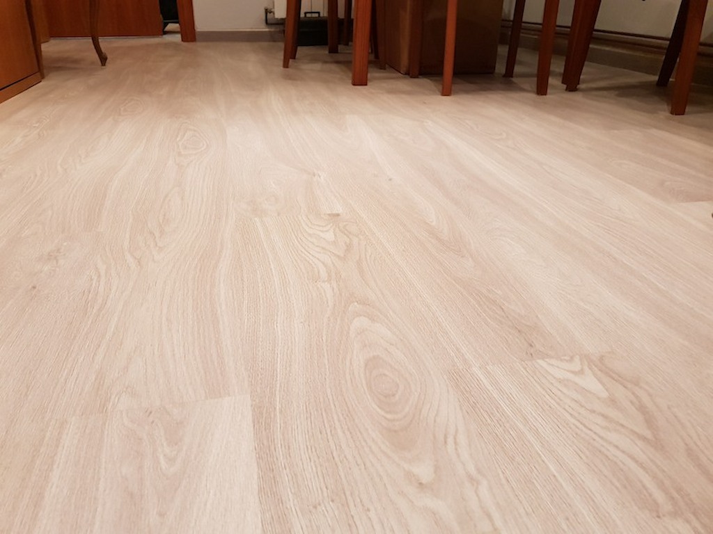 Parquet sintètic ac4 de preu econòmic amb un color clar i de textura brillant col·locat en un menjador