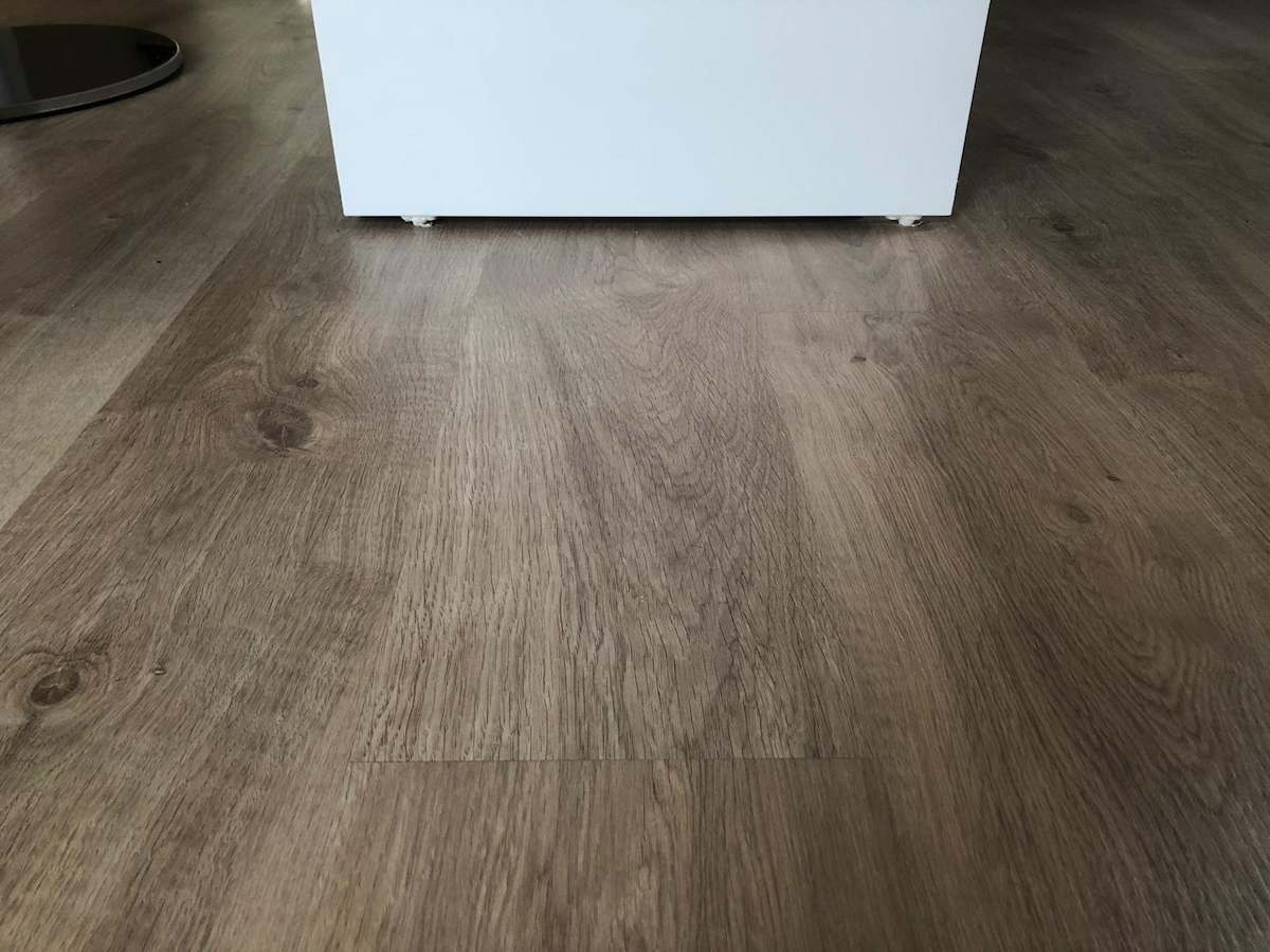 Muestra de cómo se puede poner parquet laminado roble oscuro en un interior con muebles