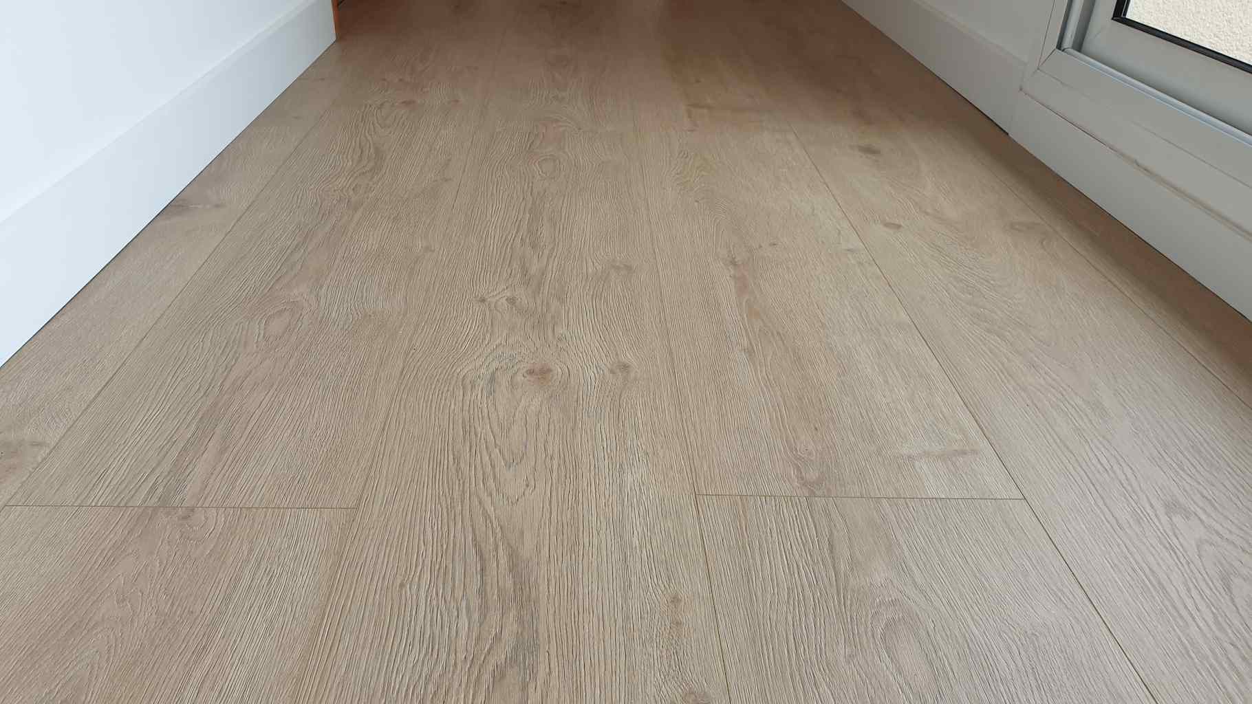 Colocación de tarima flotante resistente al agua de color claro con biselado a cuatro lados