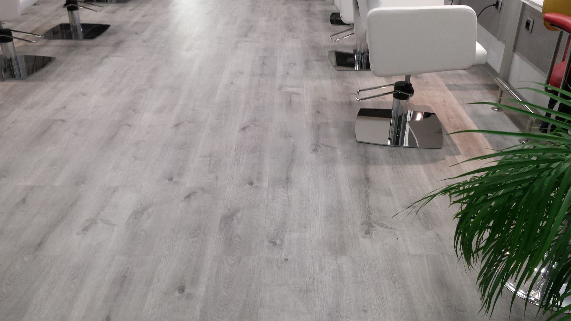 Instal·lació de parquet AC5 resistent a l'aigua de color gris a un local comercial de Mataró